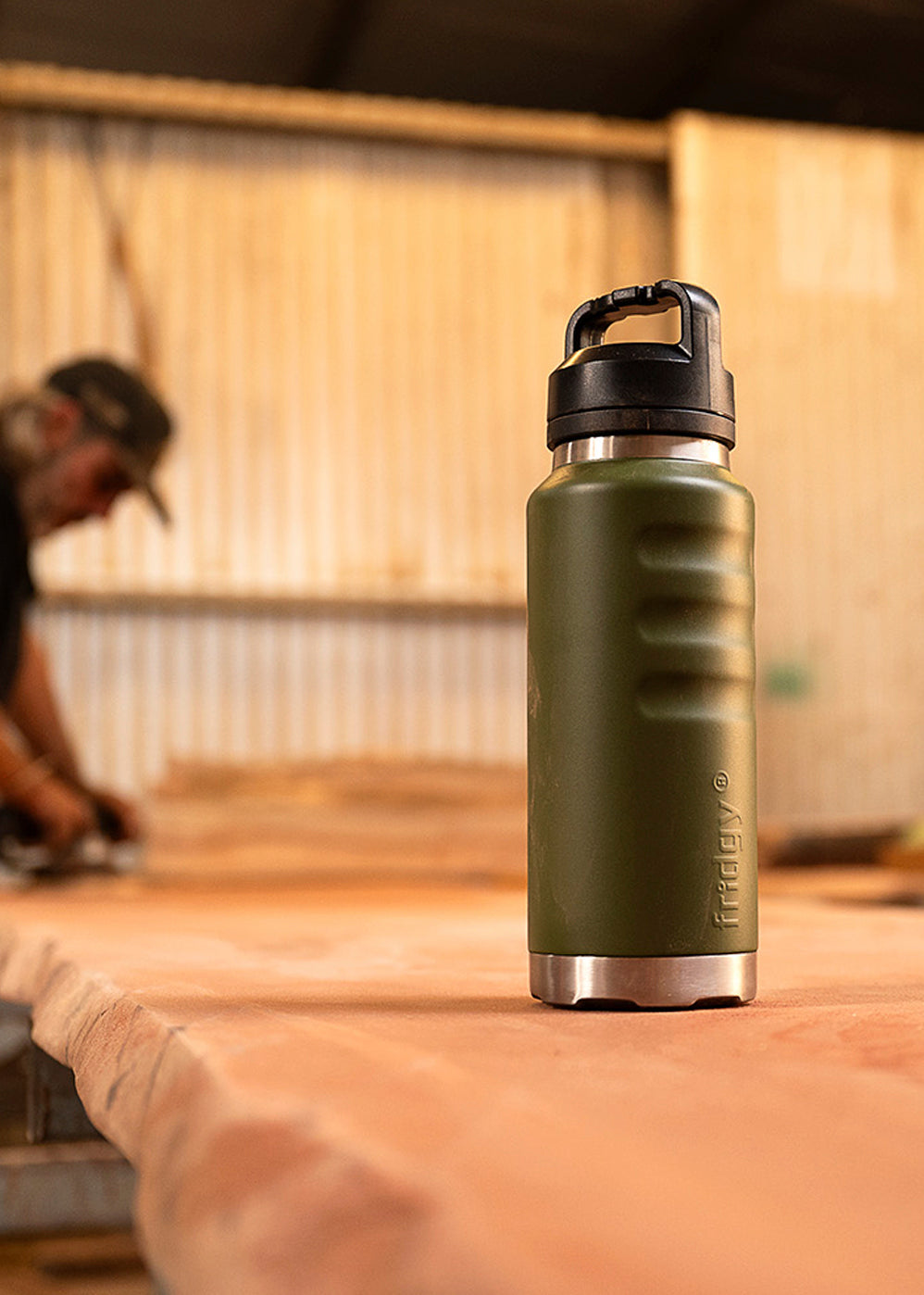 Fridgy 1080ml Grip Range Bottle in Commando Green on a workbench – Triple-wall insulated stainless steel water bottle designed for durability and all-day hydration on the job site.