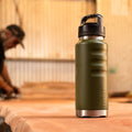 Fridgy 1080ml Grip Range Bottle in Commando Green on a workbench – Double-wall vacuum insulated stainless steel water bottle designed for durability and all-day hydration on the job site.