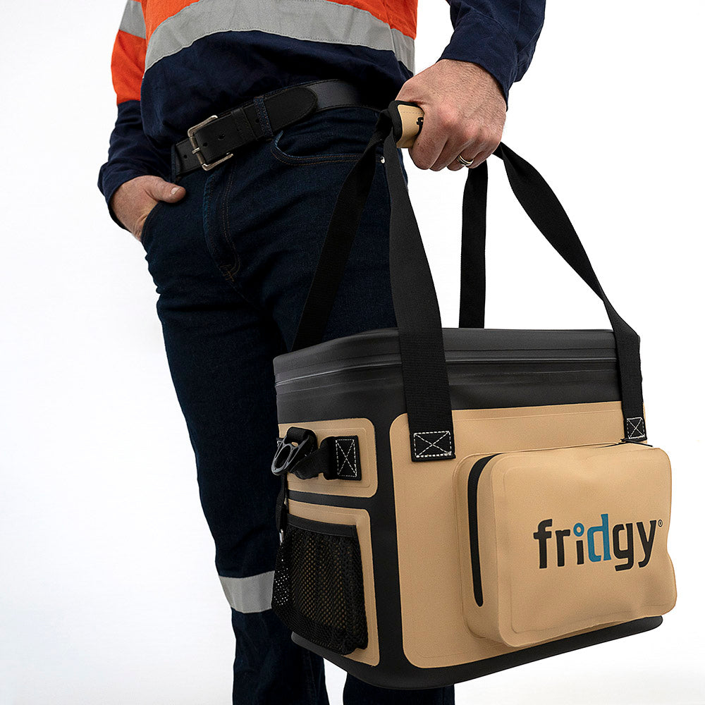 Man in high-vis holding Fridgy 14L CribMate Cooler in Sandy Taupe by its handles – Insulated soft cooler designed for durability, portability, and keeping food and drinks fresh on the job site.