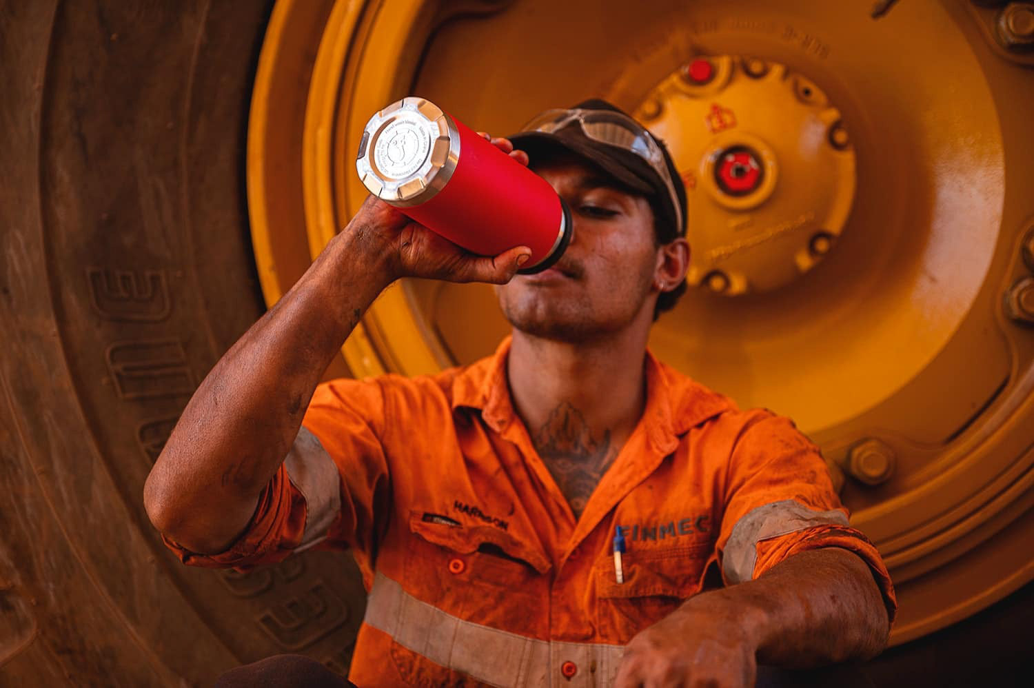 Fridgy 1080ml Grip Range Bottle – Triple-wall insulated stainless steel water bottle being used in front of a massive mining truck wheel, built for durability and all-day hydration in tough worksites.