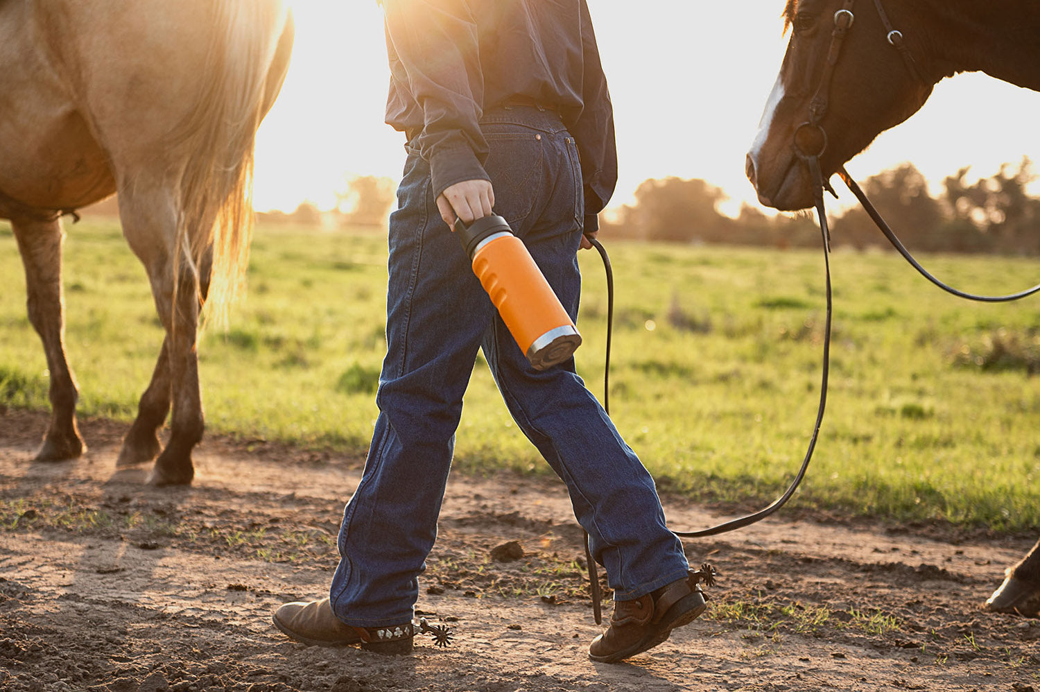 Fridgy 1080ml Grip Range Bottle – Triple-wall insulated stainless steel water bottle being held by a person walking alongside horses, designed for durable, all-day hydration.