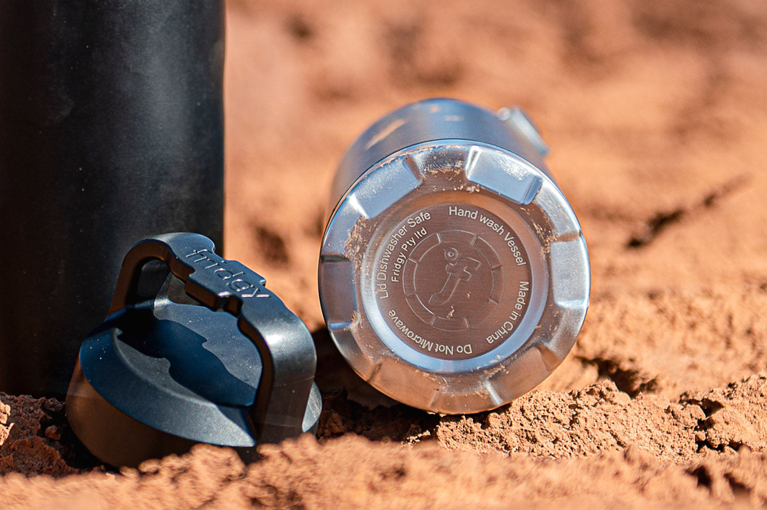 Fridgy Bottle with Tough Built Base – Close-up of the underside of a stainless steel water bottle resting on gravel, showcasing its durable, impact-resistant base.