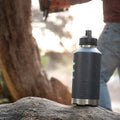 Fridgy All Dayer 1.9L water bottle on a rock with a person holding a tool in the background