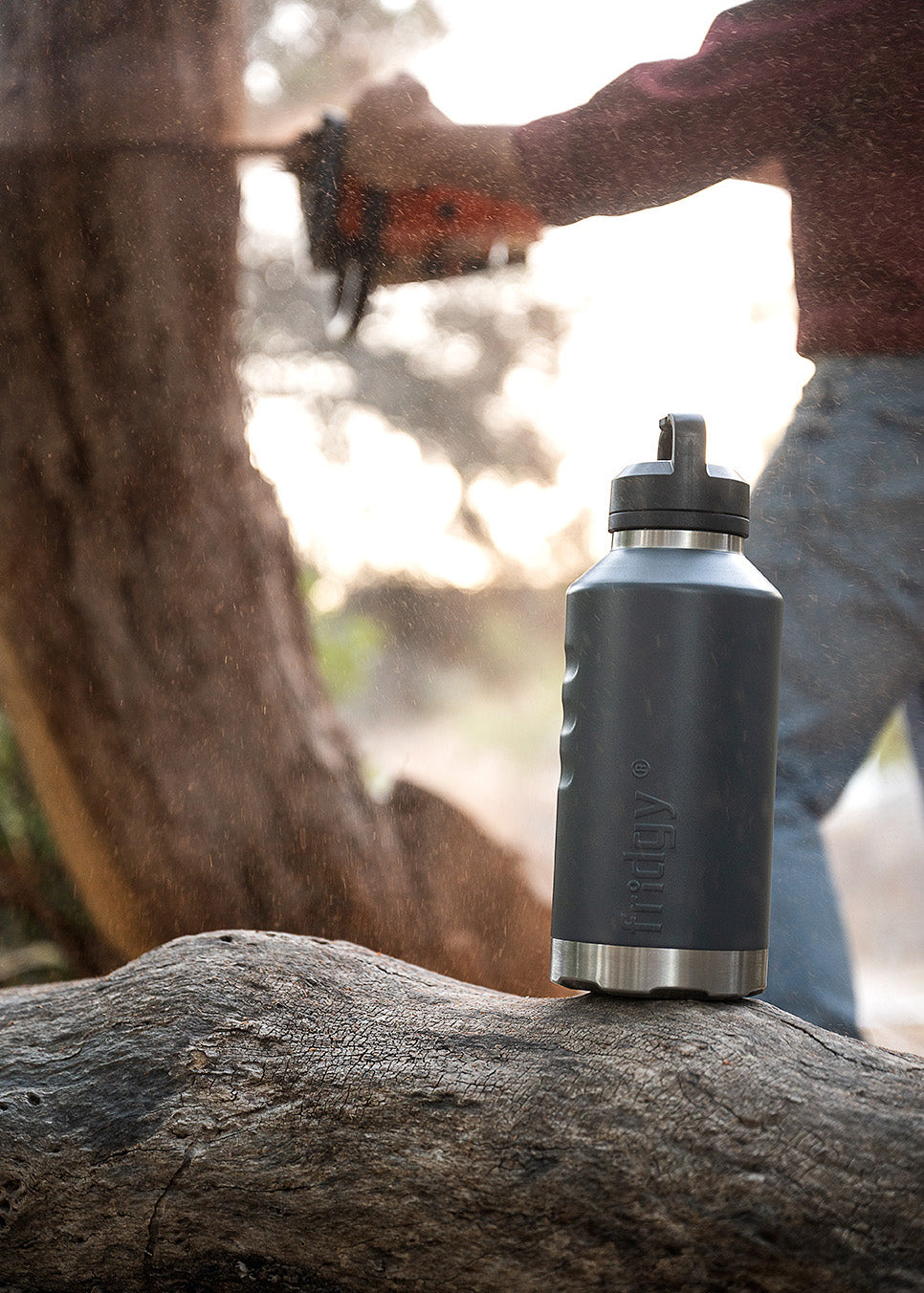 Fridgy All Dayer 1.9L water bottle on a rock with a person holding a tool in the background