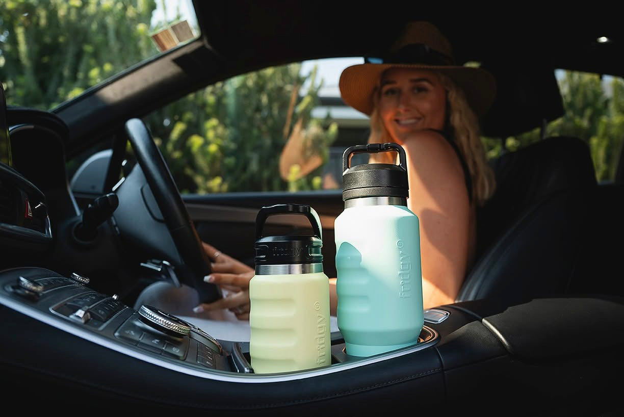 Fridgy 750ml and 1L Grip Range Bottles sitting in car cup holders – Double-wall vacuum insulated stainless steel water bottles designed for travel-friendly hydration on the go.