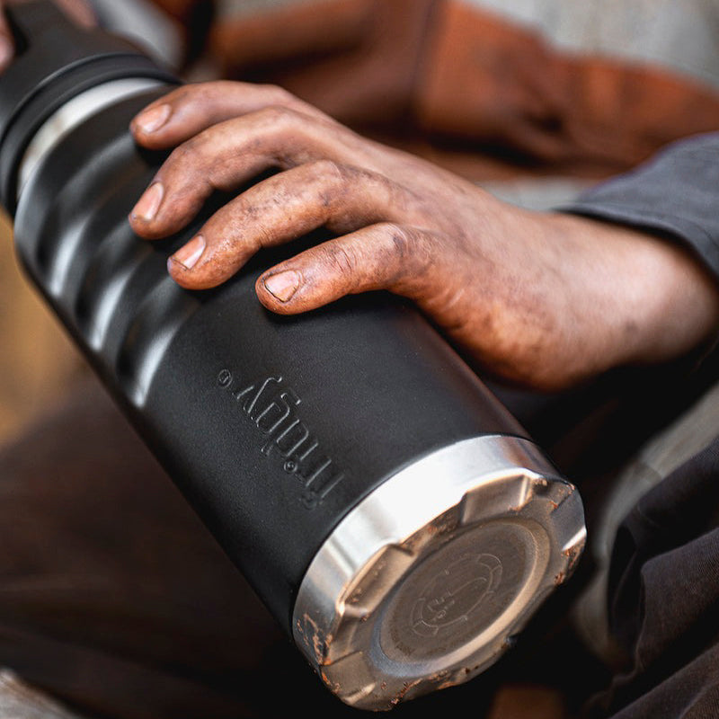 Fridgy 1080ml Grip Range Bottle in Dark Hour Black held in a dirty tradie's hand – Triple-wall insulated stainless steel water bottle built for durability and all-day hydration on the job site.