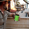 Tradie holding Fridgy Nitro Green Can Cooler with ute tray in the background – Durable, insulated stubby holder built for knock-off drinks on site.