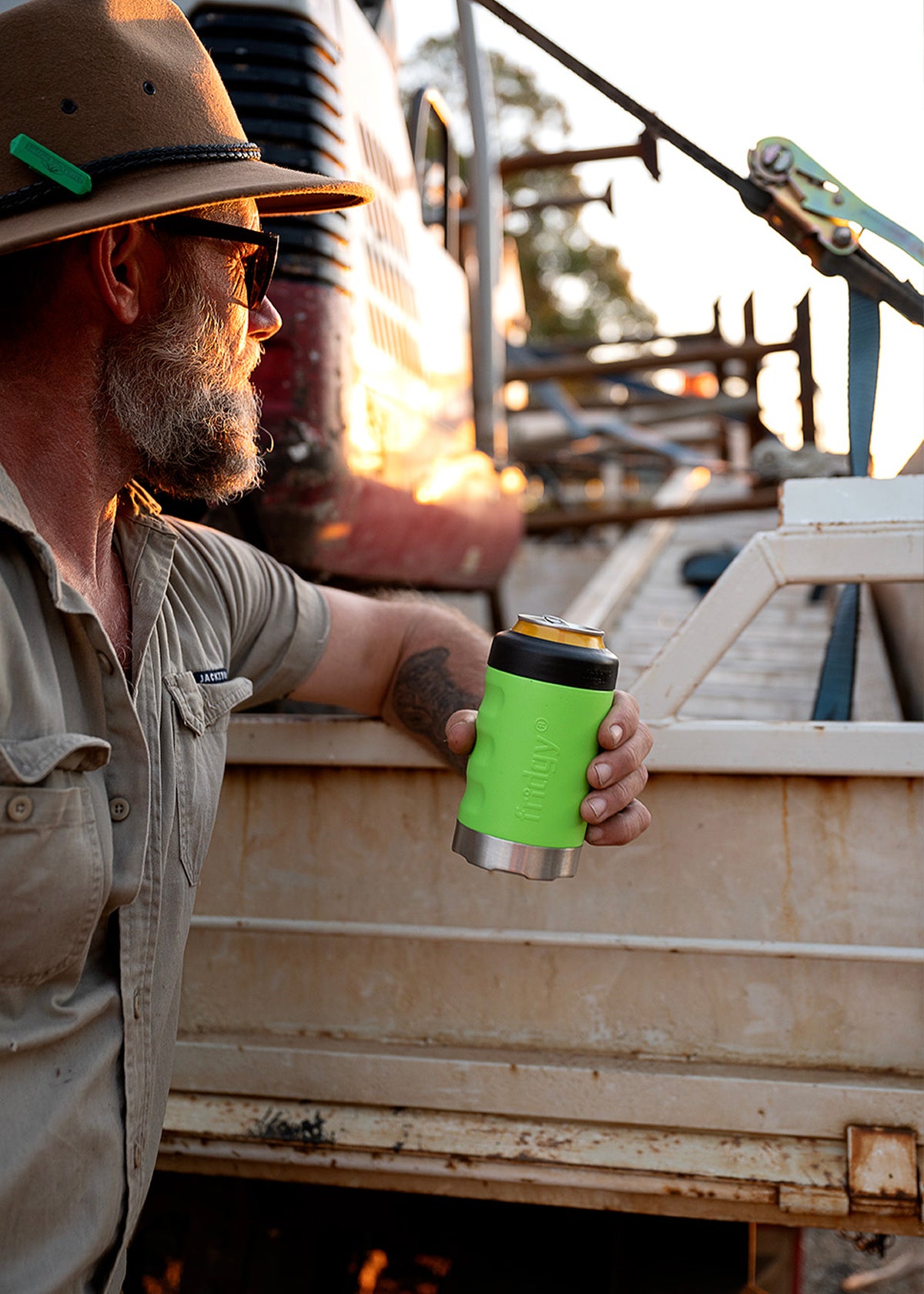 Tradie holding Fridgy Nitro Green Can Cooler with ute tray in the background – Durable, insulated stubby holder built for knock-off drinks on site.