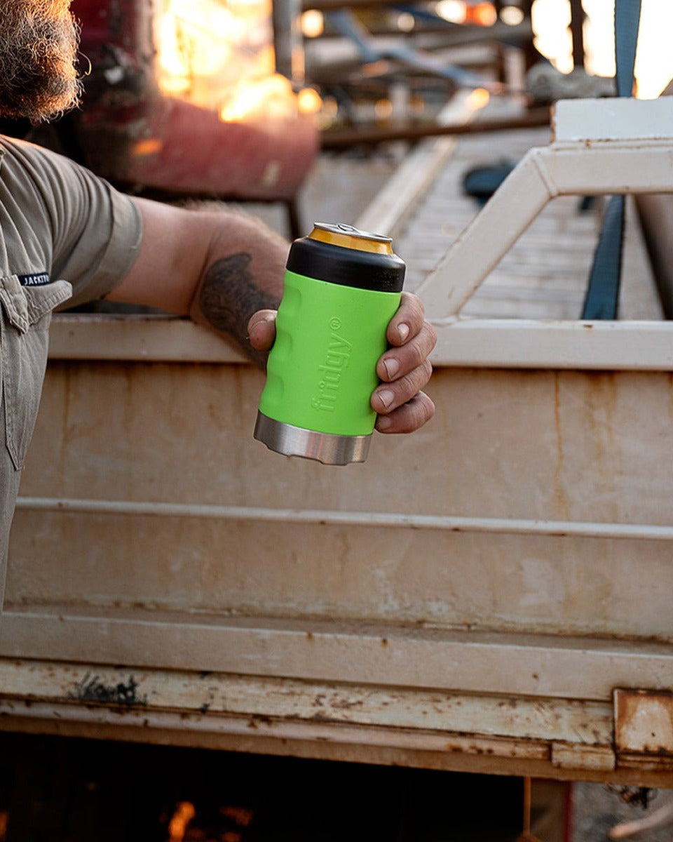 A tradie holding a nitro green Fridgy can cooler on the tray of a ute at sunset.