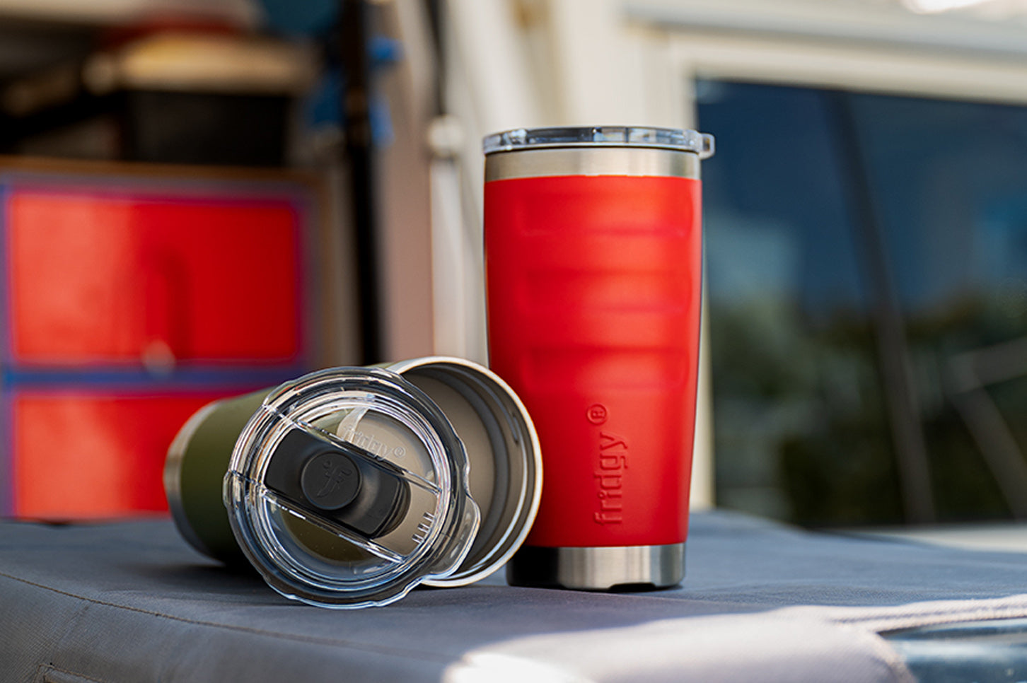 Red insulated tumbler with a silver lid on a car roof
