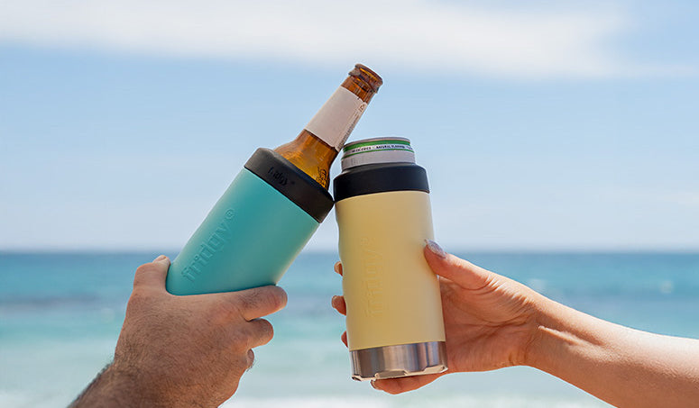 Two Fridgy SlimMate coolers raised in a cheers at the beach