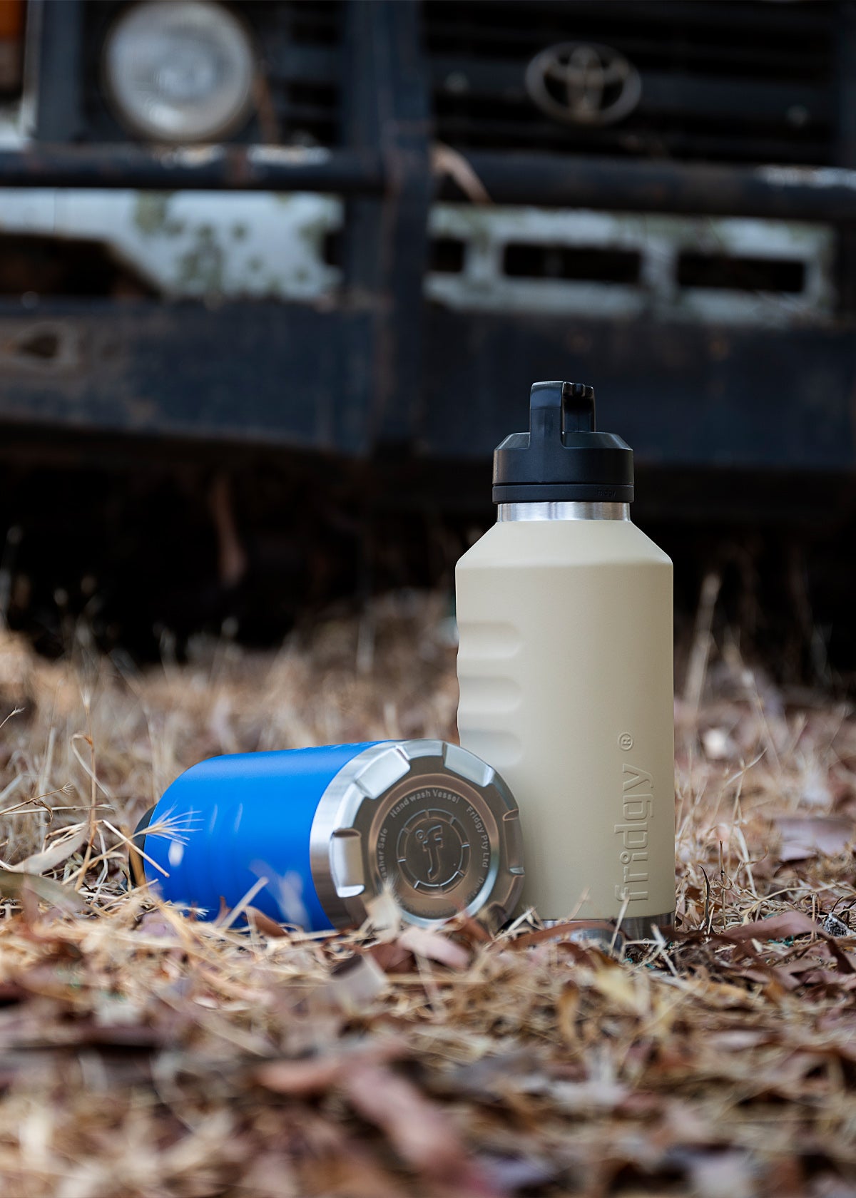 Fridgy 1.9L All-Dayer Grip Range Bottle in a rugged nature setting, placed in front of a Toyota bullbar – Triple-wall insulated stainless steel water bottle designed for all-day hydration.